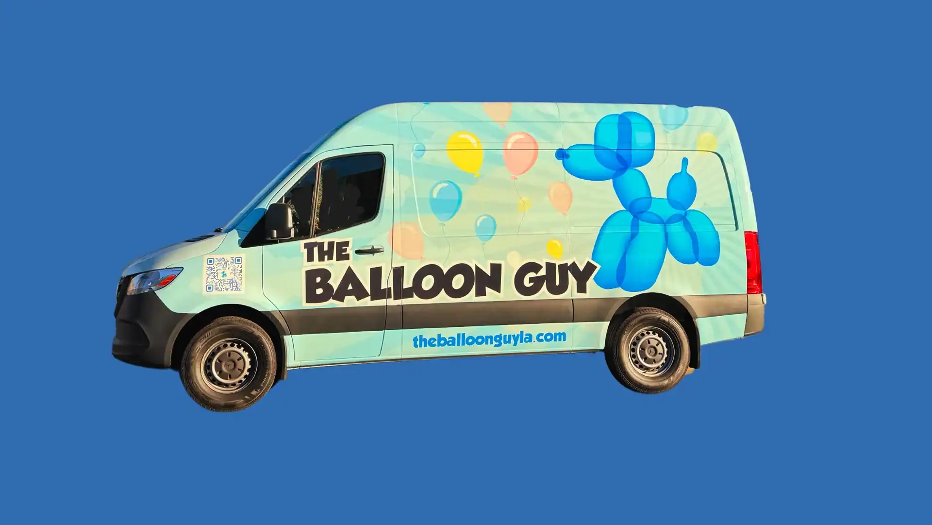 Light blue van with "The Balloon Guy" written on the side, decorated with colorful balloons and a large blue balloon dog illustration—perfect for Los Angeles balloon decor! Website: theballoonguyla.com.