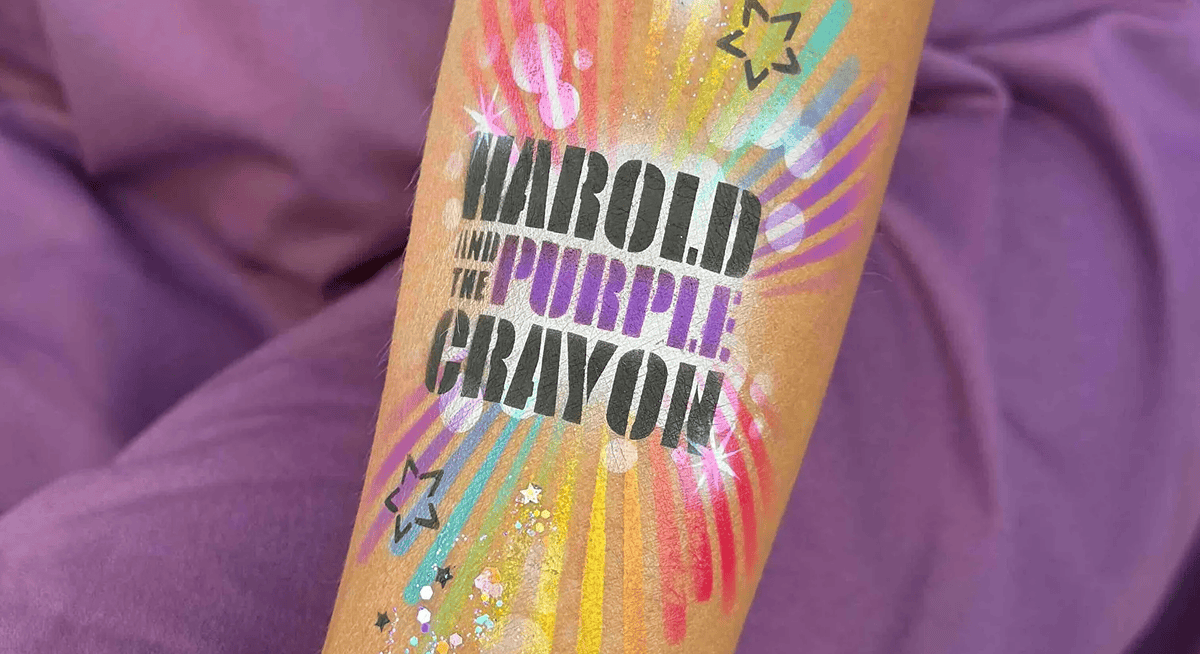 A forearm with a temporary tattoo reading "Harold and the Purple Crayon," surrounded by colorful, starburst designs, small star shapes, and festive balloon decor perfect for a corporate event.