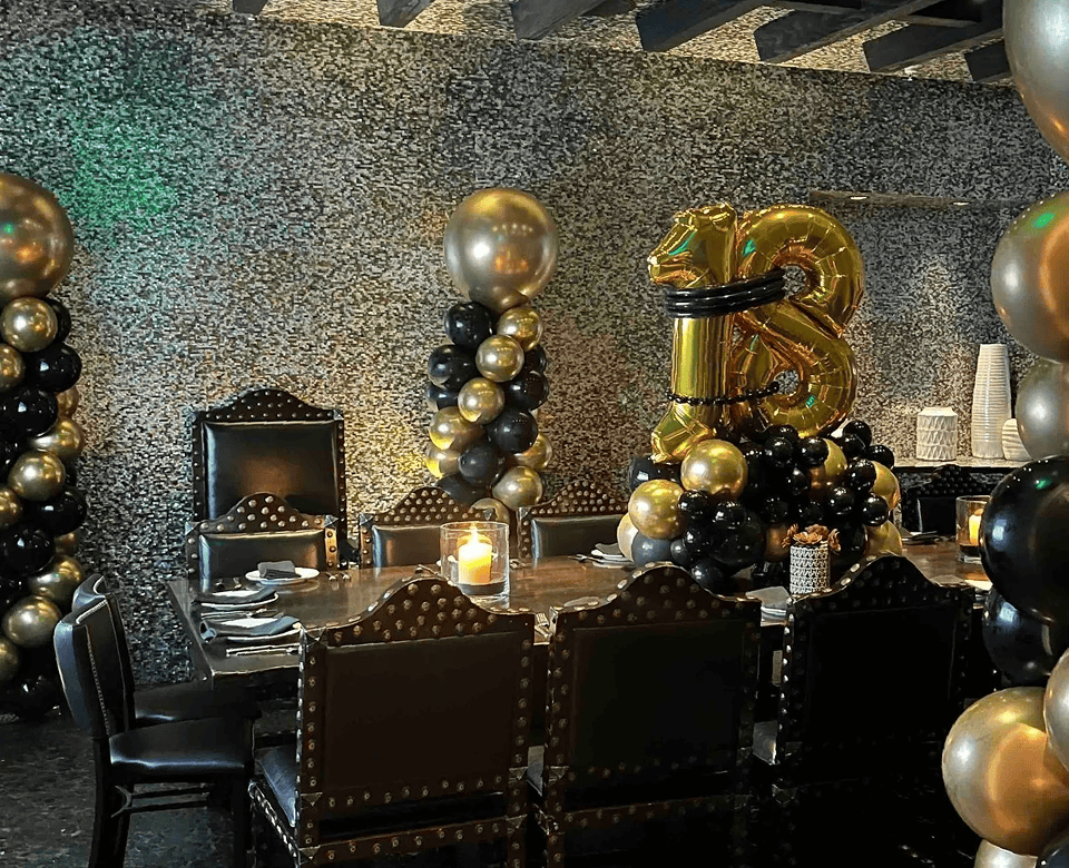 A decorated dining table with black and gold balloon installations by a talented balloon artist, featuring a large "13" balloon arrangement, perfect for a 13th birthday celebration in Los Angeles.