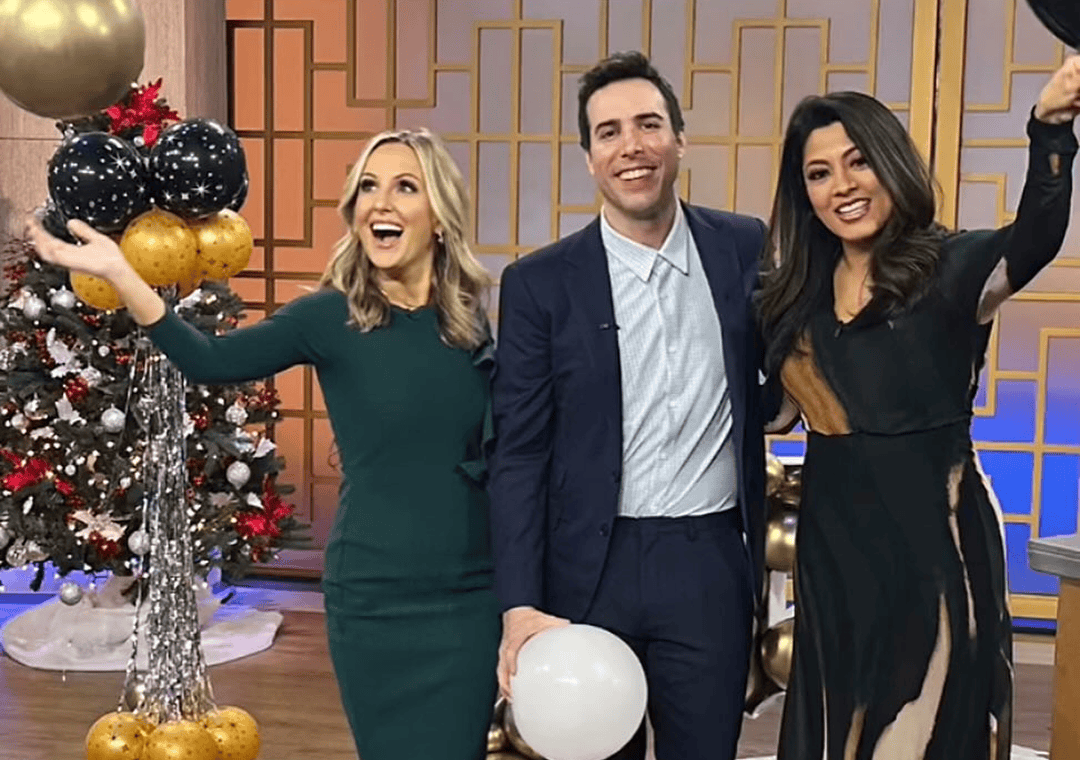 Three people dressed in formal attire stand smiling indoors near festive decorations, including balloons crafted by a talented balloon artist and a beautifully adorned Christmas tree.