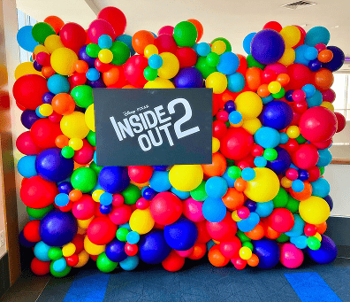 A colorful balloon wall with vibrant balloon decor and a black sign reading “Disney Pixar Inside Out 2” in white letters—perfect for adding excitement to any corporate event.
