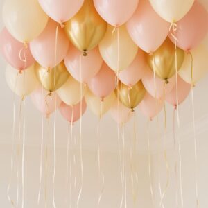 A cluster of Helium Balloons in pink, cream, and gold with long curly ribbons floats near the ceiling, creating elegant decor perfect for celebrating in Los Angeles.