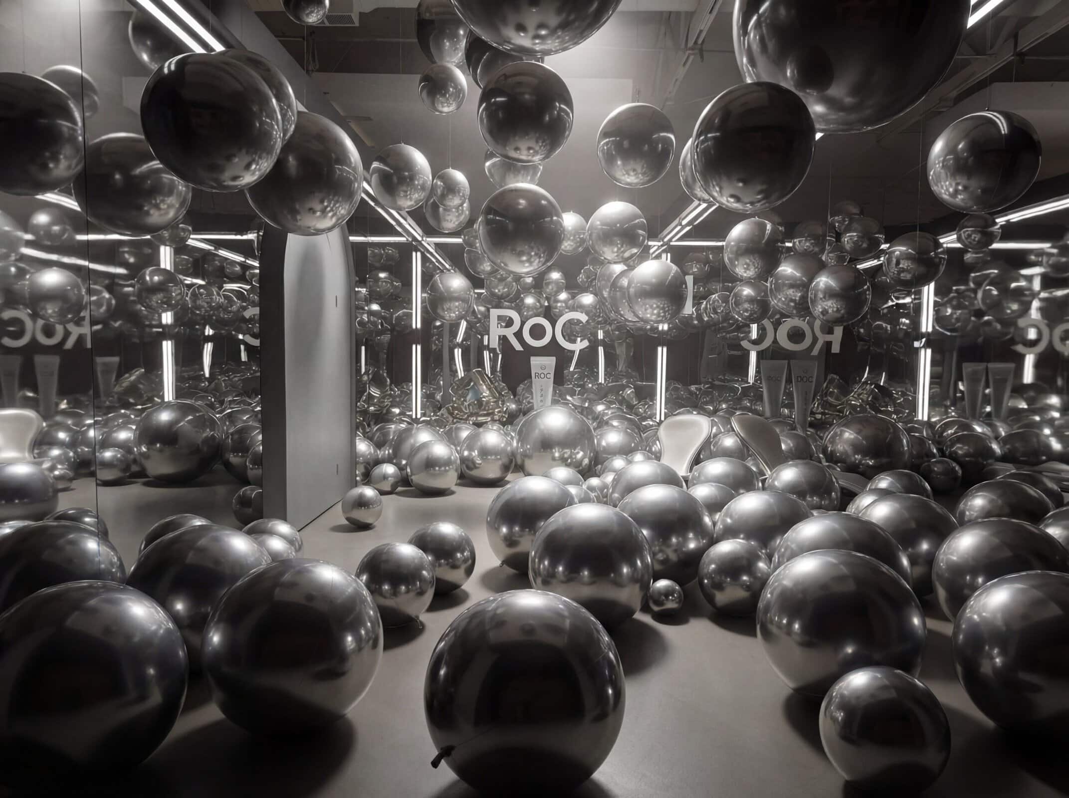 A room filled with reflective silver spheres of various sizes, surrounded by mirrored walls and bright lights, creating multiple reflections—an inspired setting perfect for memorable corporate events.