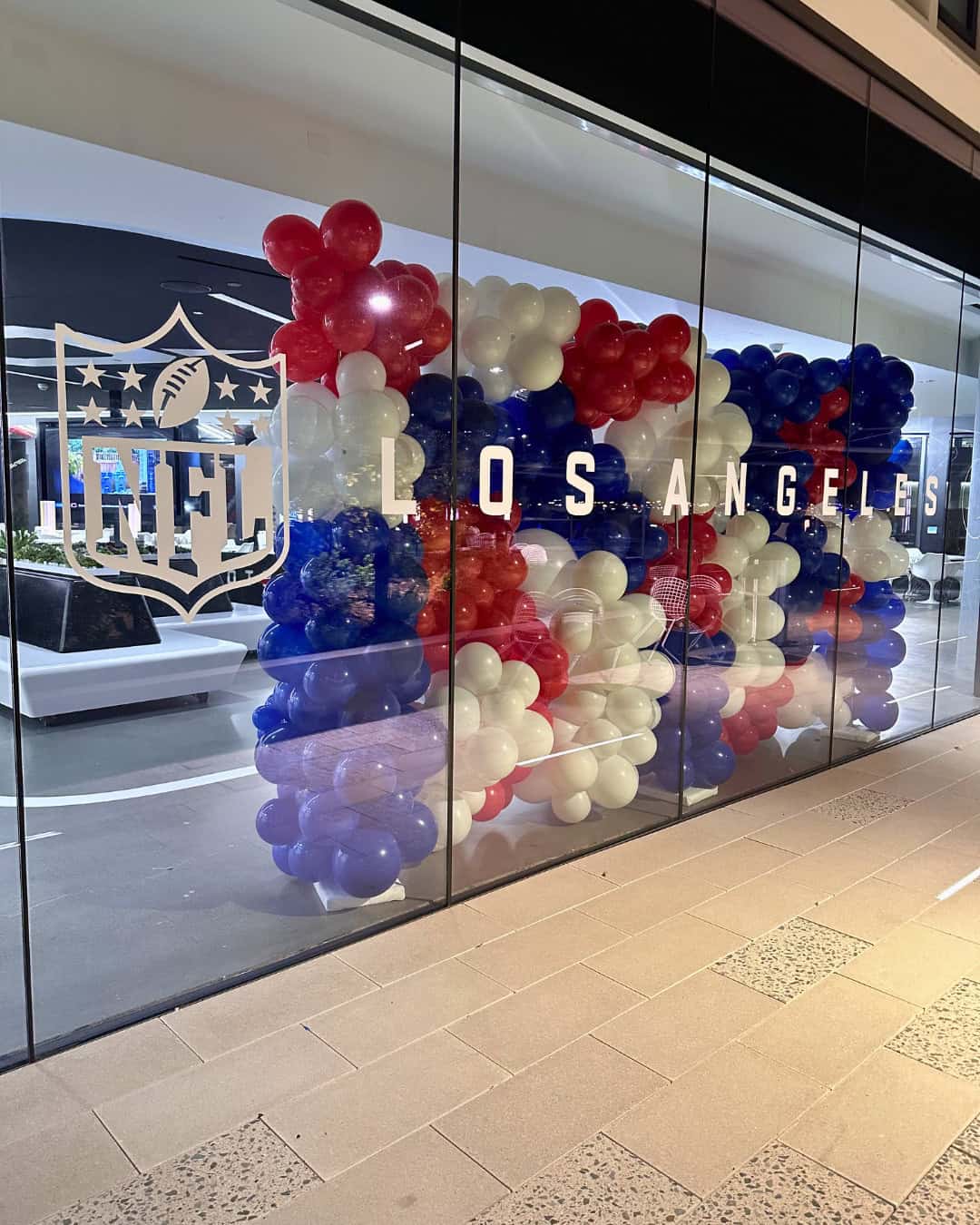 Red, white, and blue balloons are arranged behind a glass window with the NFL Los Angeles logo and text, creating a festive display perfect for Sports Events.