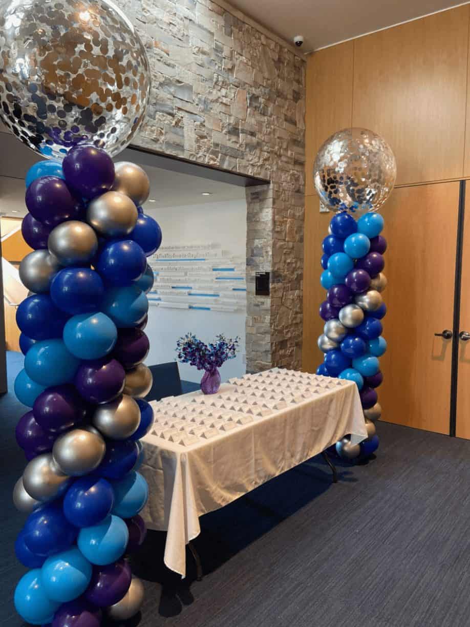 Two columns of blue and purple balloons are surrounding a table